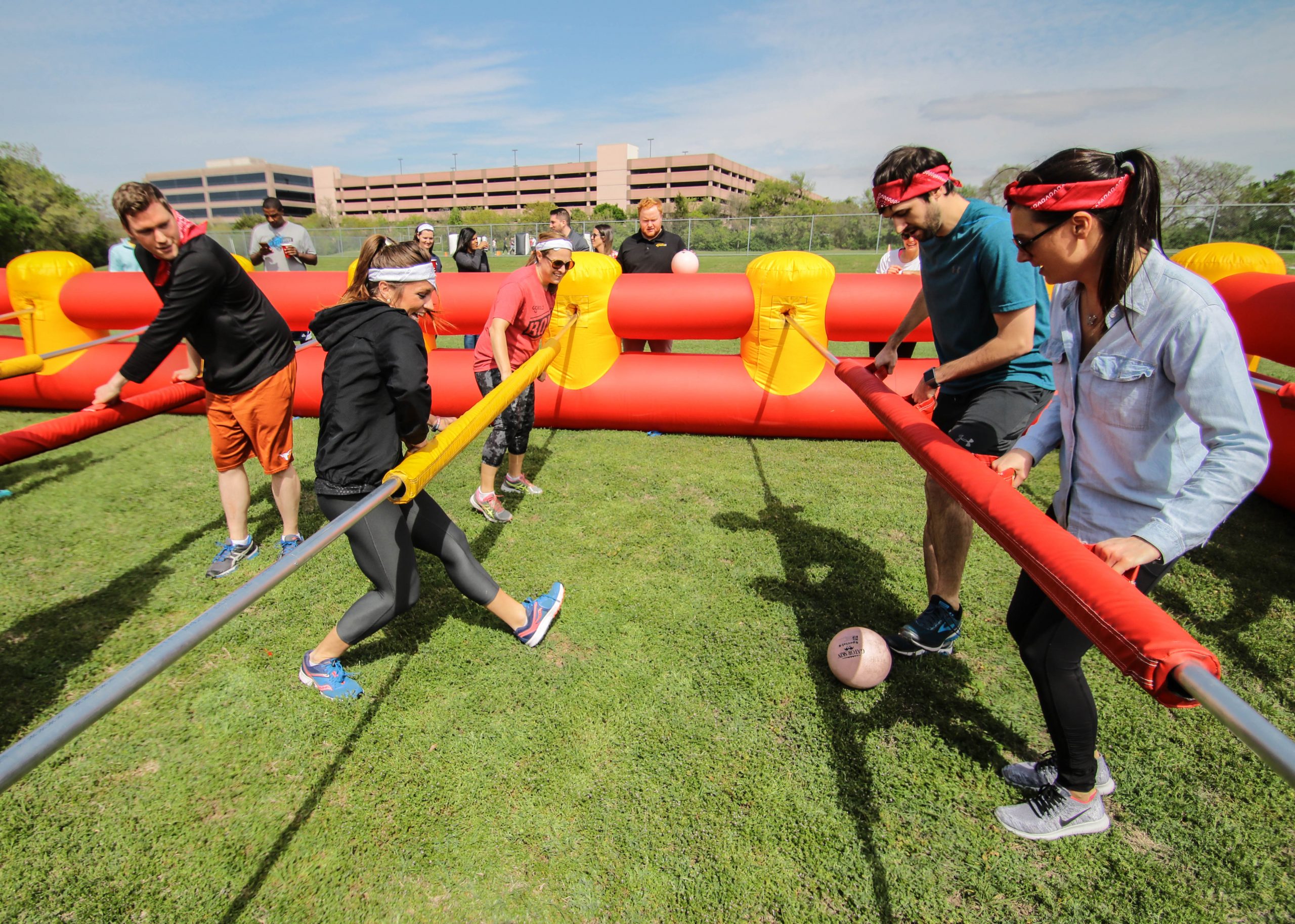 Group of adults playing human-size foosball on a green lawn during a Portable Event with Group Dynamix