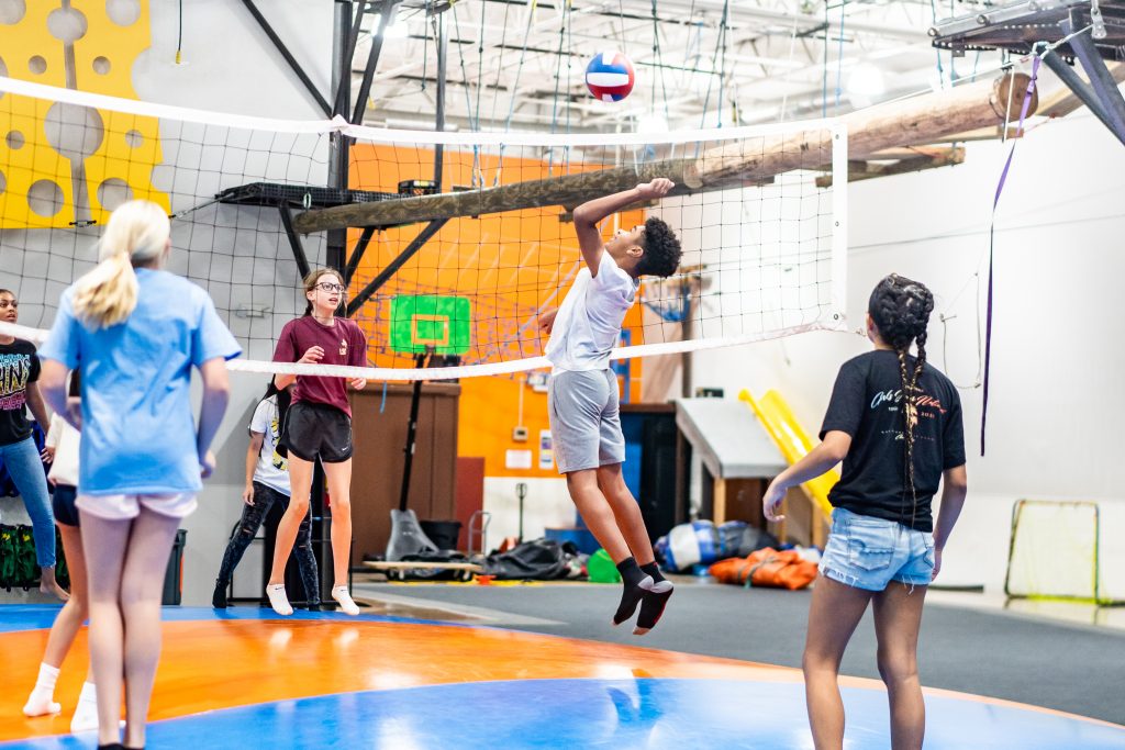 Teenage boys and girls playing volleyball on a jumping pillow at Group Dynamix