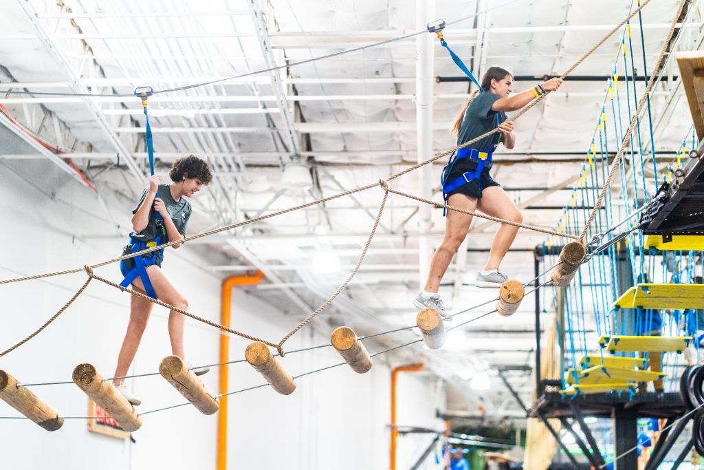 Two teenage girls on a high ropes challenge course at Group Dynamix