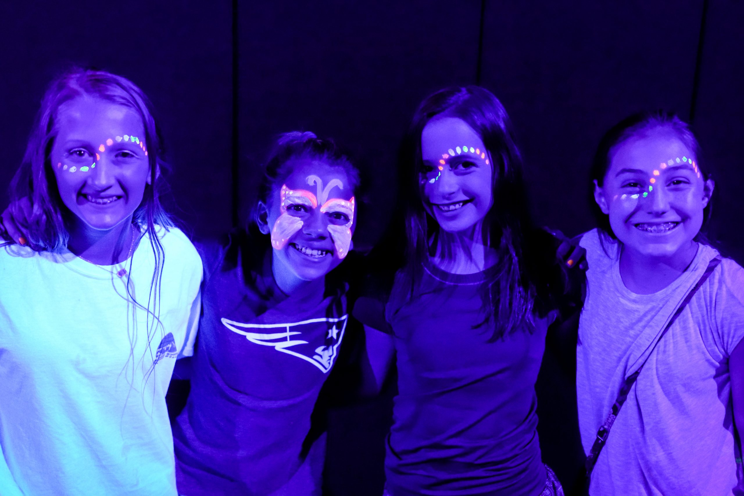4 teenagers smiling with face paint during a lock-in at Group Dynamix