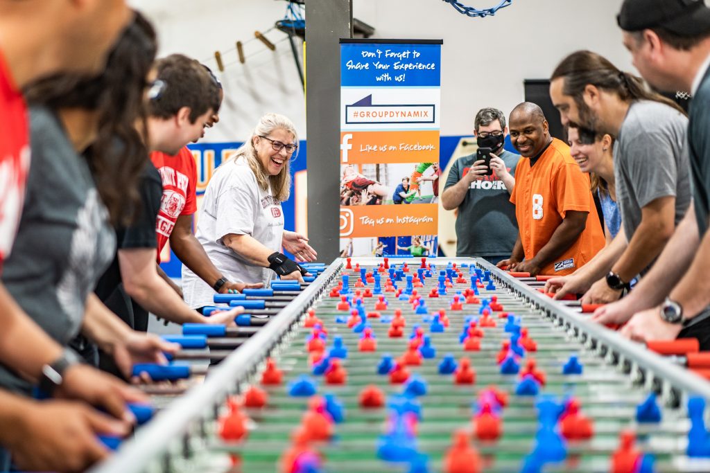 Group of adults playing foosball on a 22-player foosball table at Group Dynamix