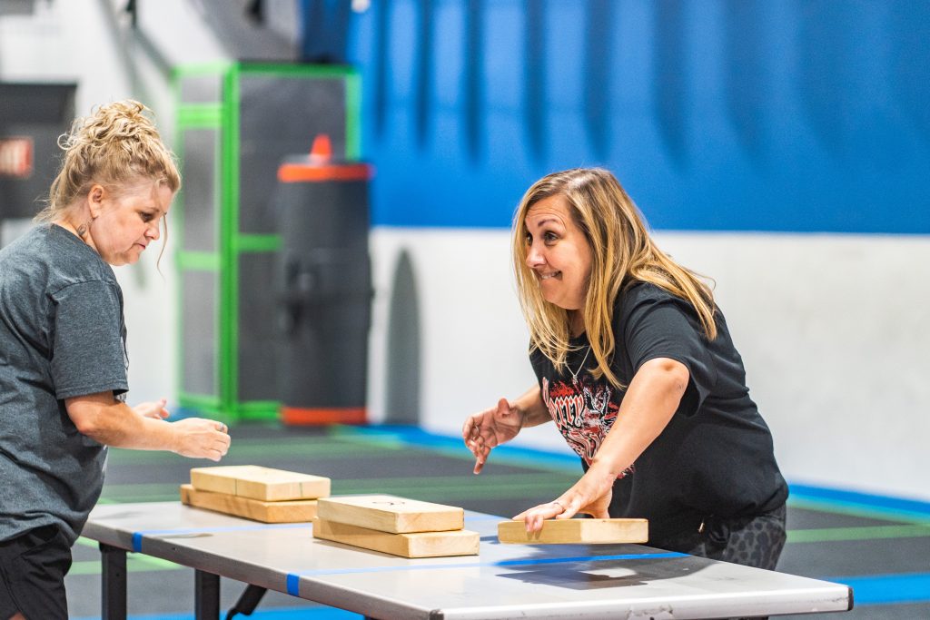 Two midle-aged ladies playing a table-top game with wooden blocks during an adult event at Group Dynamix