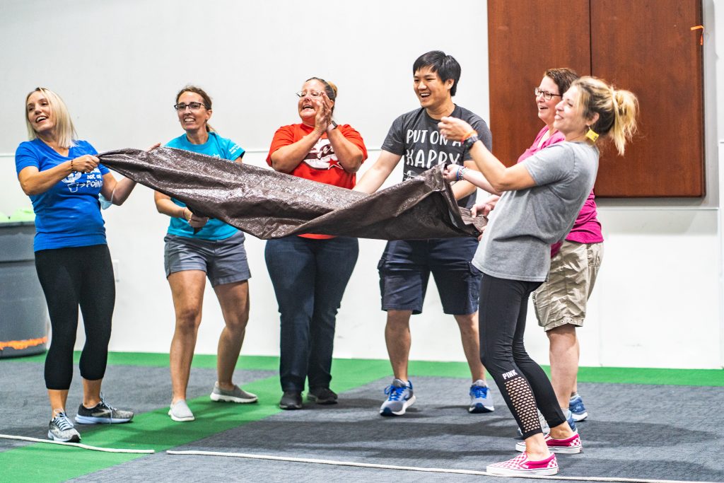 Group of educators playing a team building game with a tarp