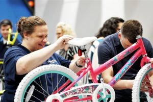 Lady smiling as she assembles a bicycle with her colleagues for a charity event at Group Dynamix