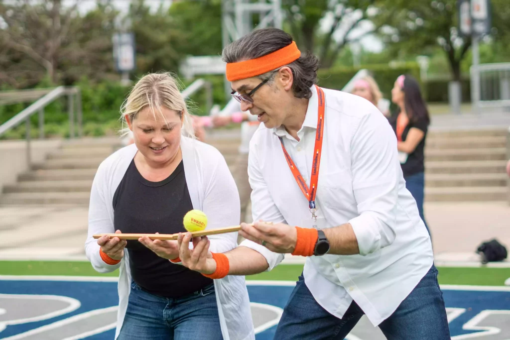 A man and a lady play gutter ball with a tennis ball during a team building event