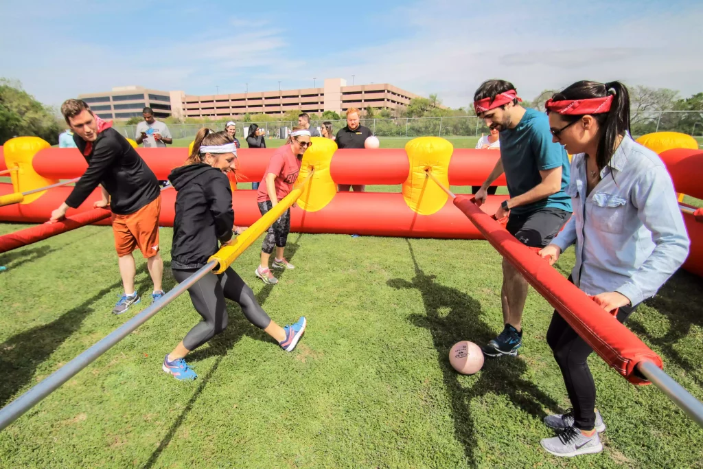 Group of adults playing human-size foosball during a portable event