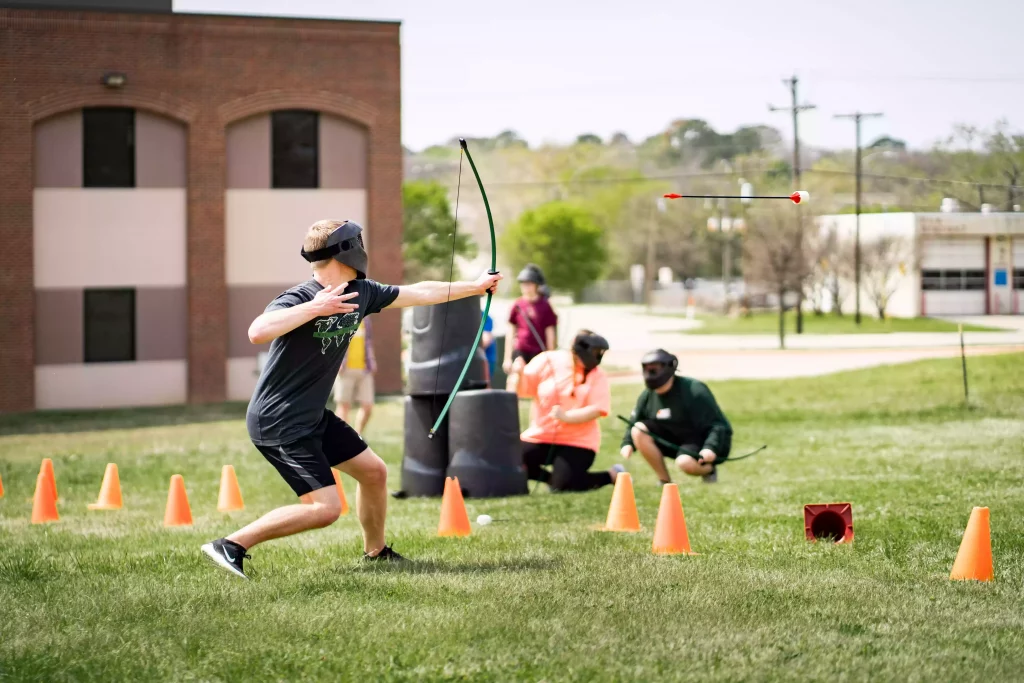 Teenage boy shooting an arrow during an archery tag game at a portable event