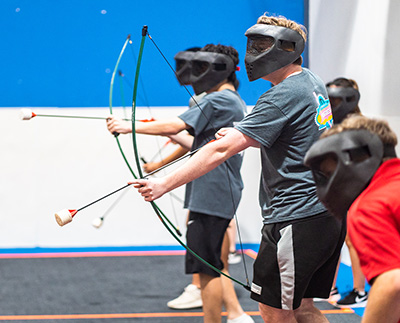Teenagers holding bows and arrows during a game of archery tag at Group Dynamix