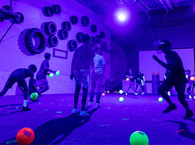 Teenagers playing blacklight dodgeball during a team building event at Group Dynamix