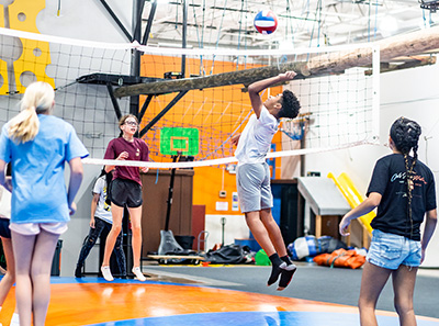 Teenagers jumping on an inflatable pillow and playing volley ball during a birthday party at Group Dynamix
