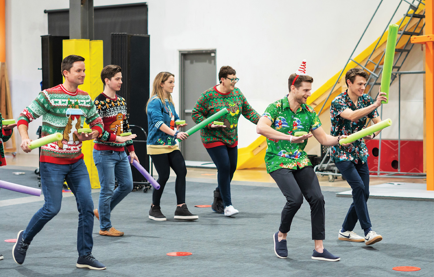 Colleagues enjoying food, drinks, and games during a holiday event dressed in holiday sweaters