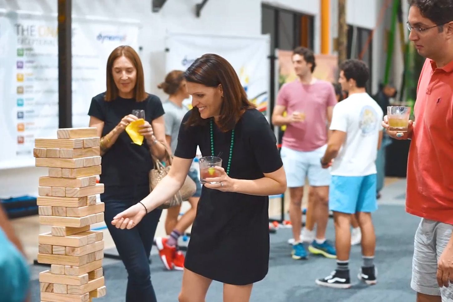 lady smiling and playing giant jenga while socializing with her co-workers during a holiday celebration