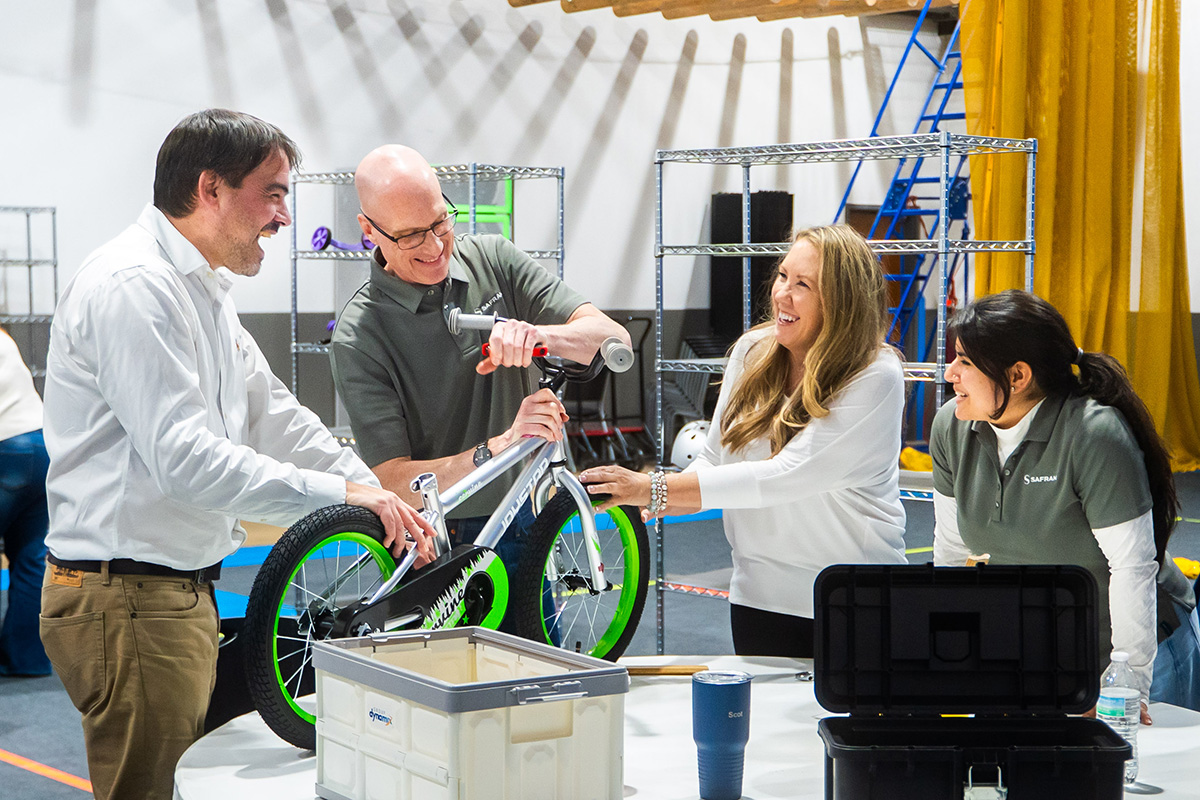 Two co-workers putting together a bike for kids during a charity event