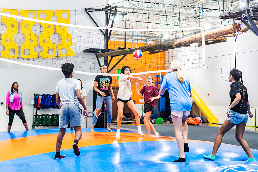 Three teenage girls smiling on a high ropes course at Group Dynamix