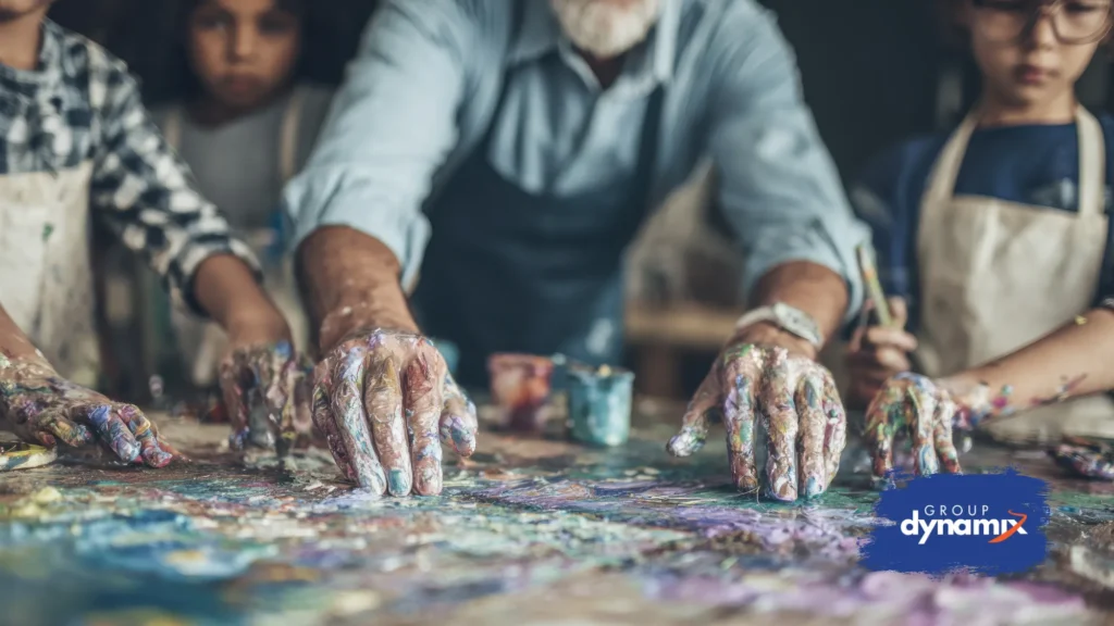 Students and teacher participating in hands-on experiential learning with a collaborative painting activity, demonstrating interactive education and team building skills, with Group Dynamix logo.