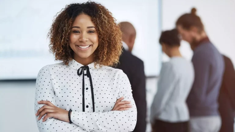 Confident team leader standing in office helping build high performing teams.